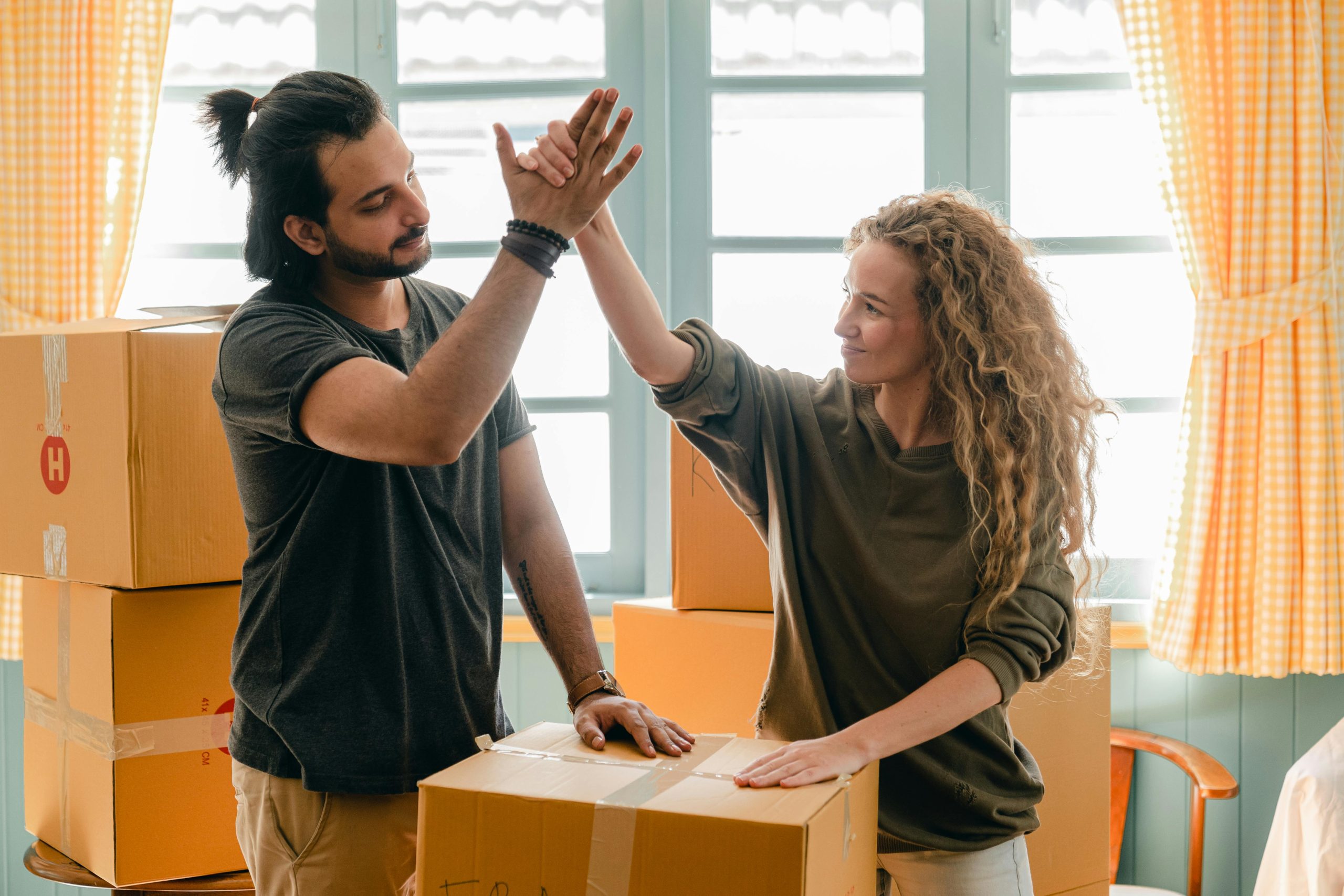 photo of two people doing a high five in a house with moving boxes all around them