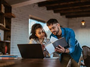 understanding the true cost of homeownership - adult man and woman sitting at a table looking at a notebook together